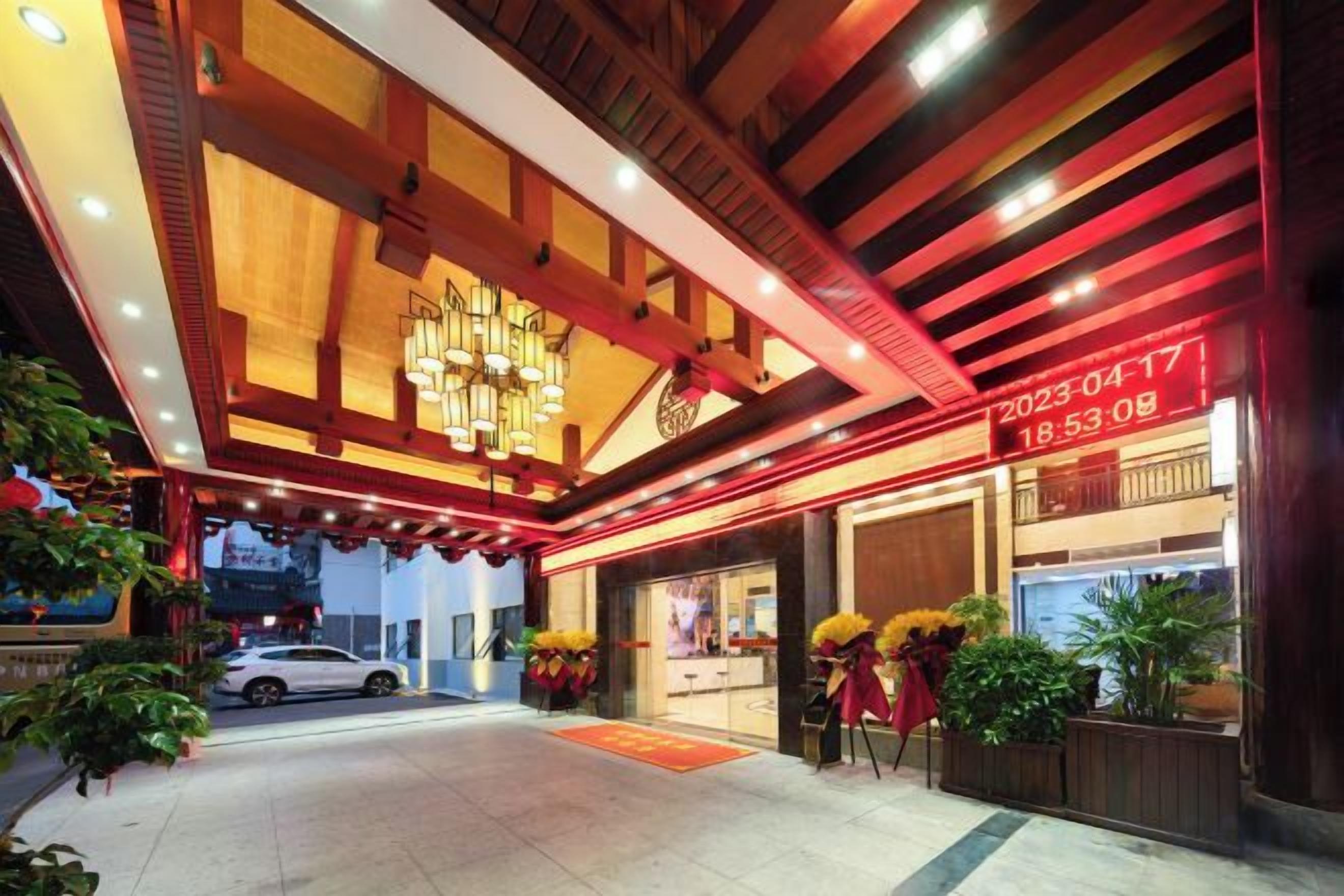 A hotel entrance with a modern design, a digital clock, and a car parked outside.