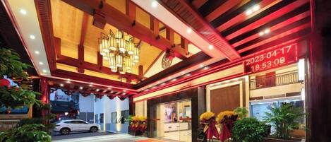 A hotel entrance with a modern design, a digital clock, and a car parked outside.