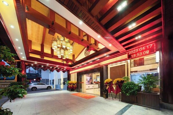A hotel entrance with a modern design, a digital clock, and a car parked outside.