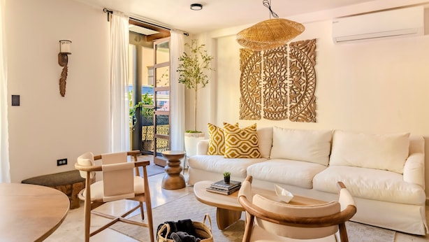 Ein modernes Wohnzimmer mit einem weißen Sofa, einem Couchtisch und einem Essbereich mit einem runden Tisch und Stühlen.