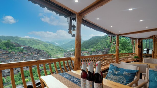 Una mesa de madera con botellas y vistas a un pueblo montañoso.