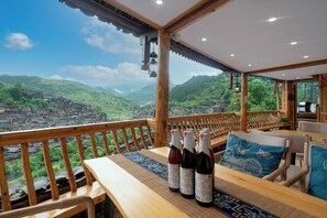 Une table en bois, avec des bouteilles dessus, et une vue sur un village de montagne.