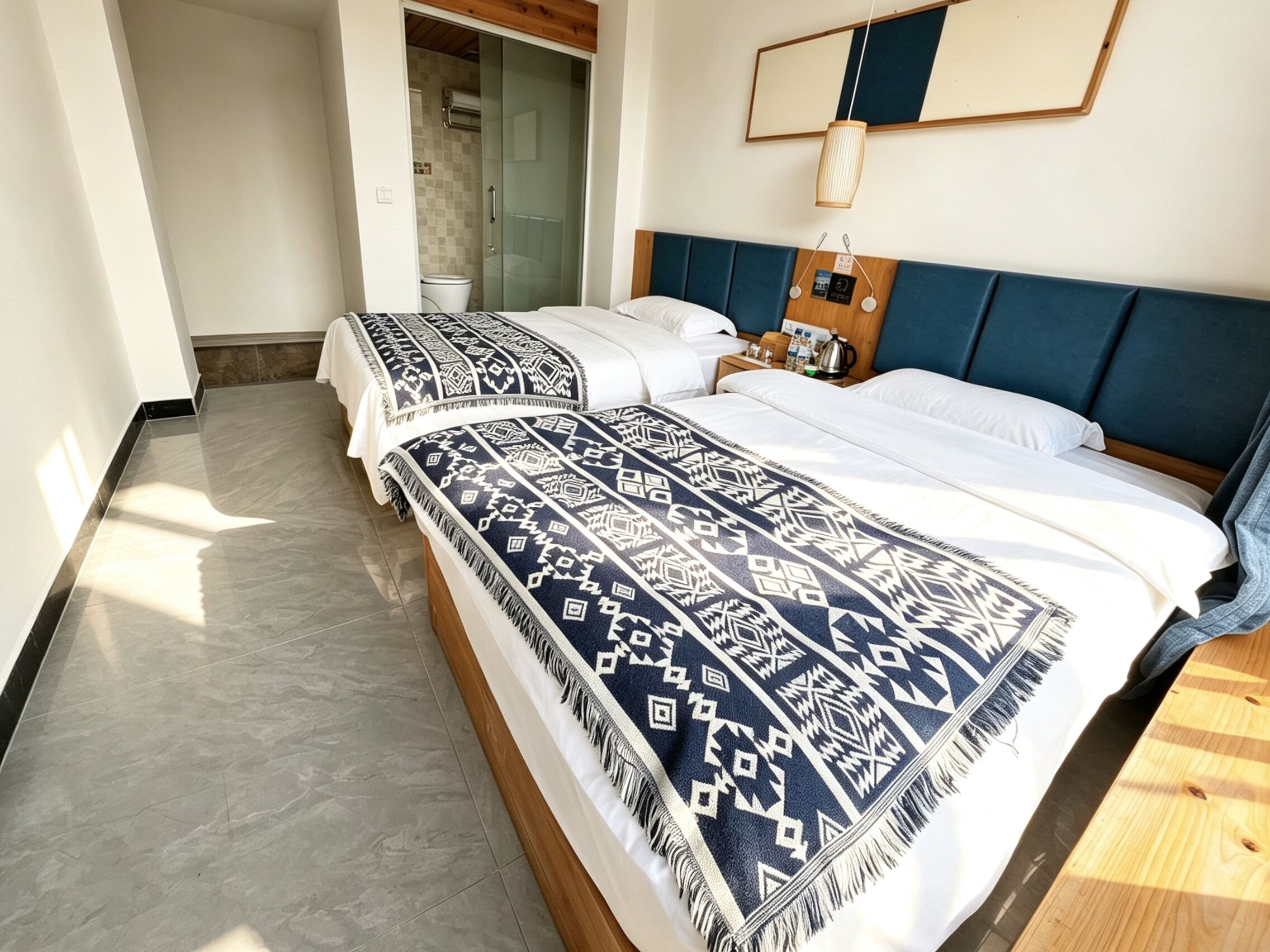 A hotel room with a large bed, a wooden headboard, a bedside table with a lamp, and a view of the bathroom.
