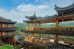 A traditional multi-story building with wooden balconies and tiled roofs, featuring a restaurant area with tables and chairs. - Xijiang Yunting Light Luxury Panoramic (Qiandongnan)