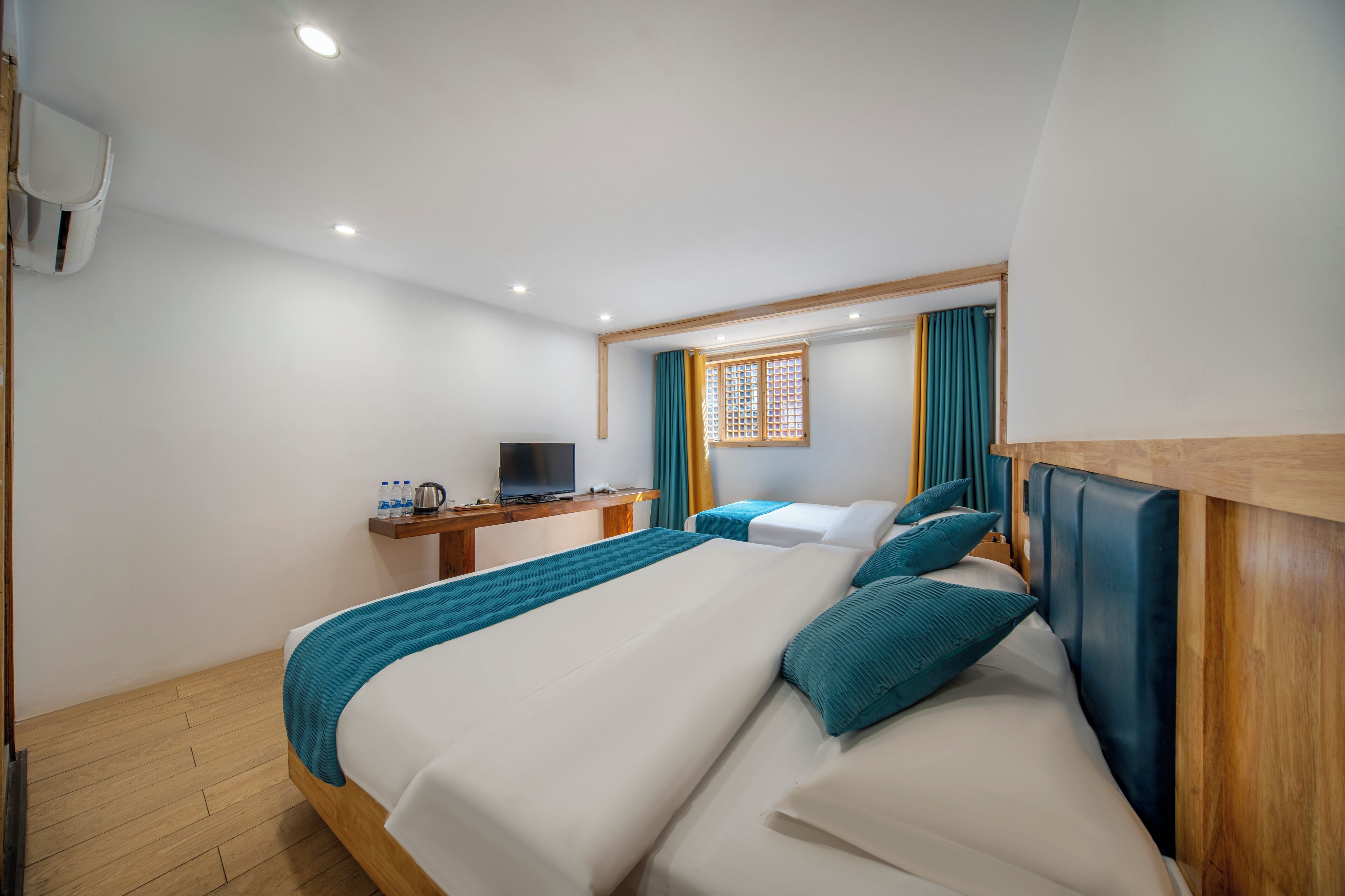 A hotel room with a large bed, a TV, a desk, and a window with curtains.