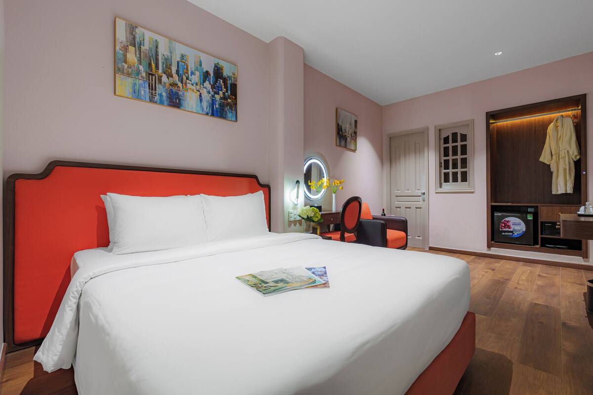 Habitación de hotel con una cama grande, un tocador con espejo, un televisor y una bata colgada en la puerta.