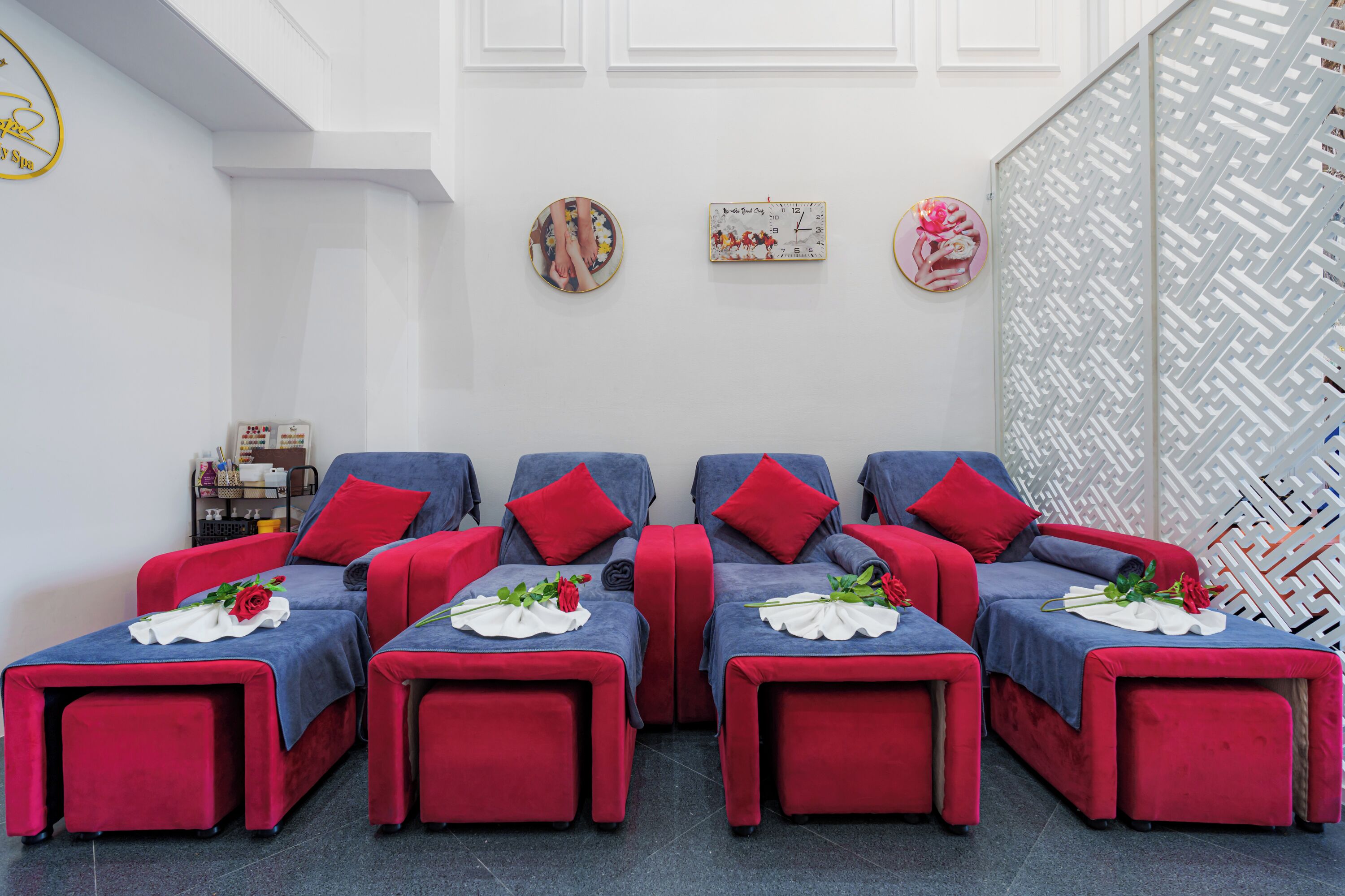 A spa room with four massage chairs, each with a red cushion and a white towel.