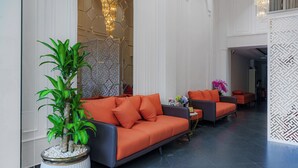 A modern lobby with a large potted plant, orange sofas, and a decorative wall with a geometric pattern. - Salute Saigon Hotel and Spa (Ho Chi Minh City)