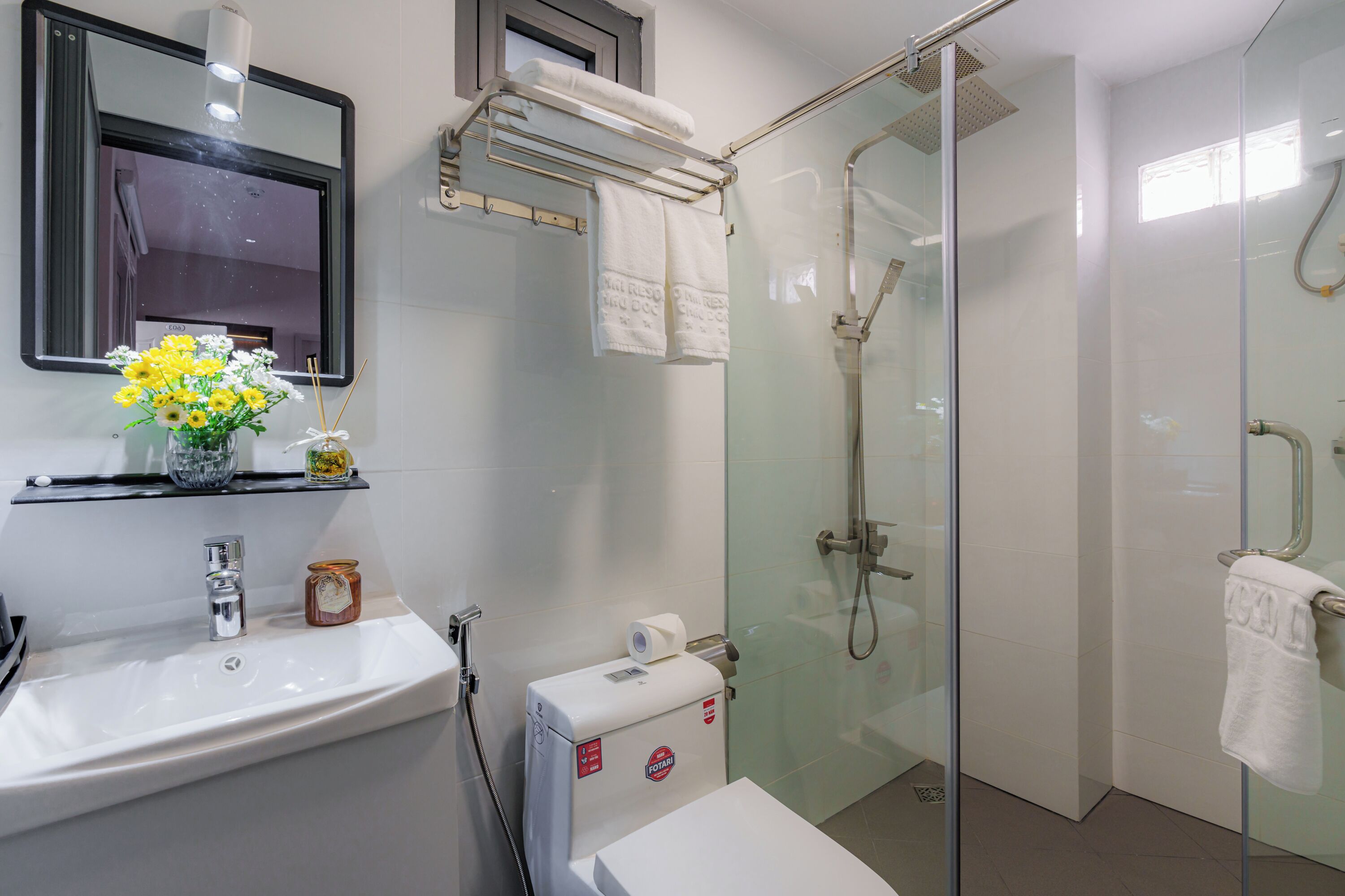 A modern bathroom with a glass-enclosed shower, a white sink, and a mirror above the sink.