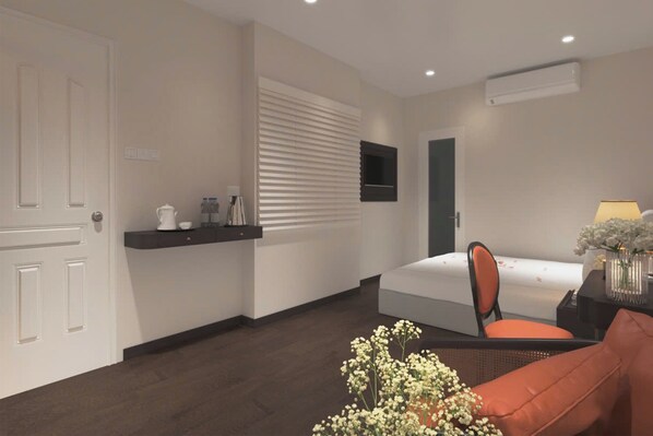 A modern hotel room with a bed, a seating area with a chair, a small table with a lamp, and a wall-mounted TV.