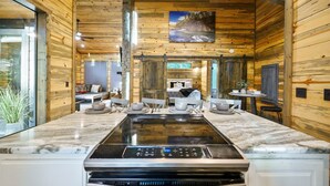 Une cuisine moderne dotée d’un grand îlot central, de murs en bois et d’un coin repas avec un canapé et une table.
