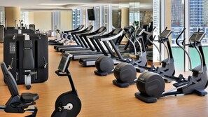 Un gimnasio con cintas de correr, bicicletas estáticas y máquinas de pesas.