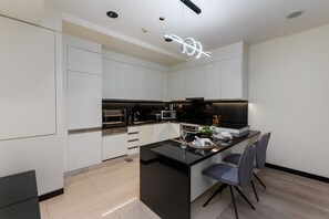 A modern kitchen with white cabinets, a black countertop, and a central island with seating.