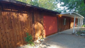 A wooden fence, a red garage door, and a covered porch area. - Creekfront 3-bedroom house with WiFi, AC in Happy Camp (Happy Camp)