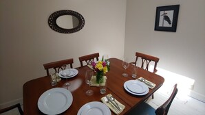 A dining room with a wooden table set for four, including plates, glasses, and cutlery. - Creekfront 3-bedroom house with WiFi, AC in Happy Camp (Happy Camp)