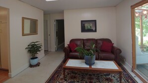A living room with a brown leather sofa, a coffee table, a potted plant, a framed picture on the wall, and a skylight above. - Creekfront 3-bedroom house with WiFi, AC in Happy Camp (Happy Camp)