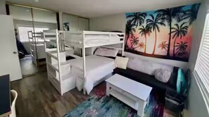 Een kleine kamer met een stapelbed, een slaapbank en een kleurrijke muurschildering.