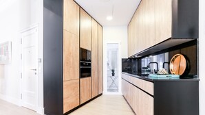Une cuisine moderne avec des meubles en bois, un réfrigérateur noir et un plan de travail équipé d’appareils de cuisine.
