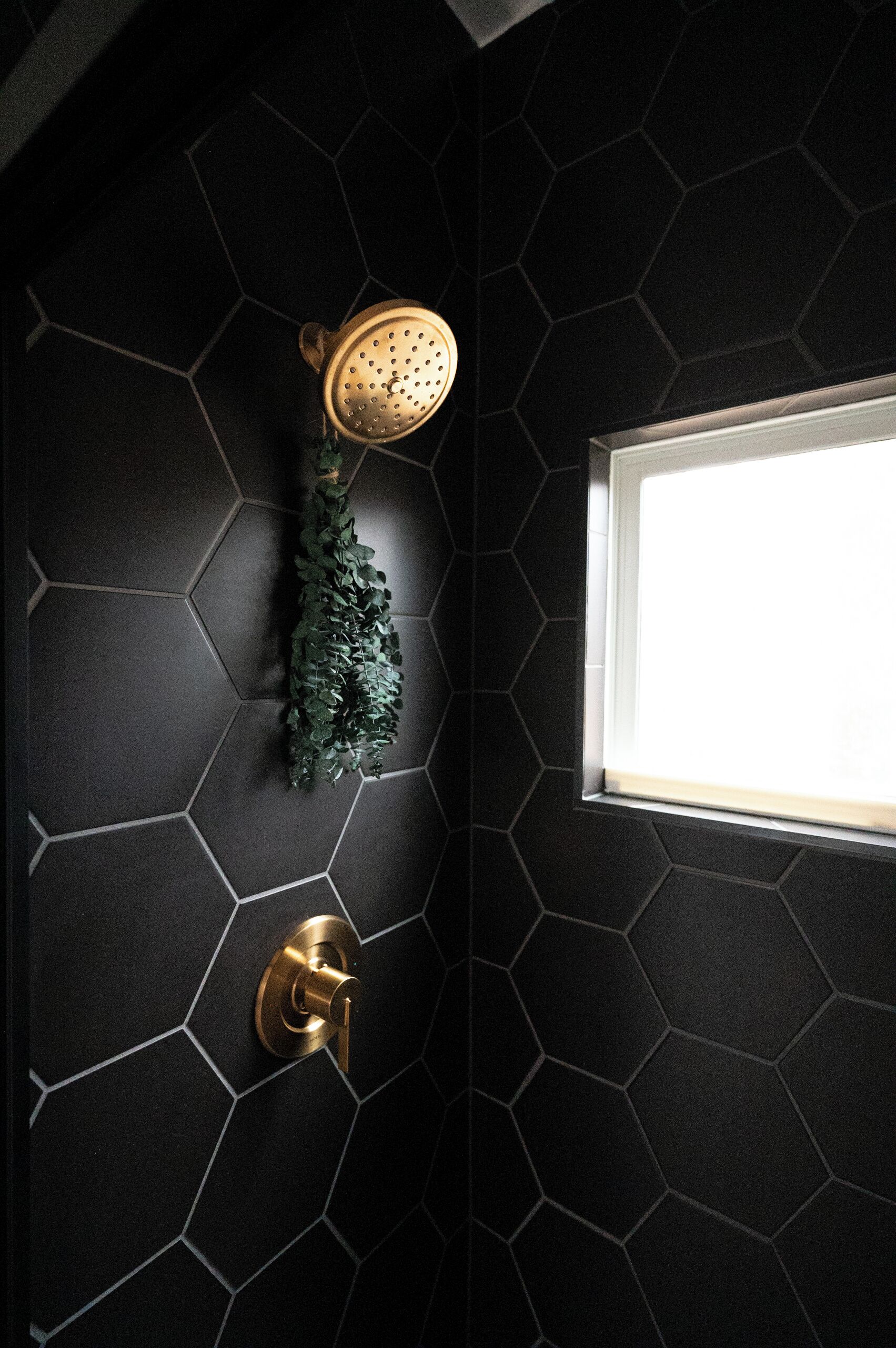 Une salle de bain avec une douche, une fenêtre et une porte dotée d’une poignée en laiton.