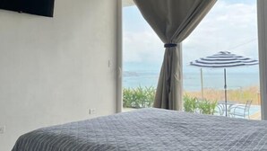 Een slaapkamer met een bed, een aan de muur bevestigde televisie en een raam met gordijn.