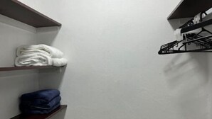 Een smalle inloopkast met houten planken, waarvan er een gevouwen witte handdoeken bevat en een andere gevouwen blauwe handdoeken.