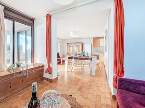 Un espacio habitable amplio con piso de madera, una mesa de comedor y una cocina al fondo.