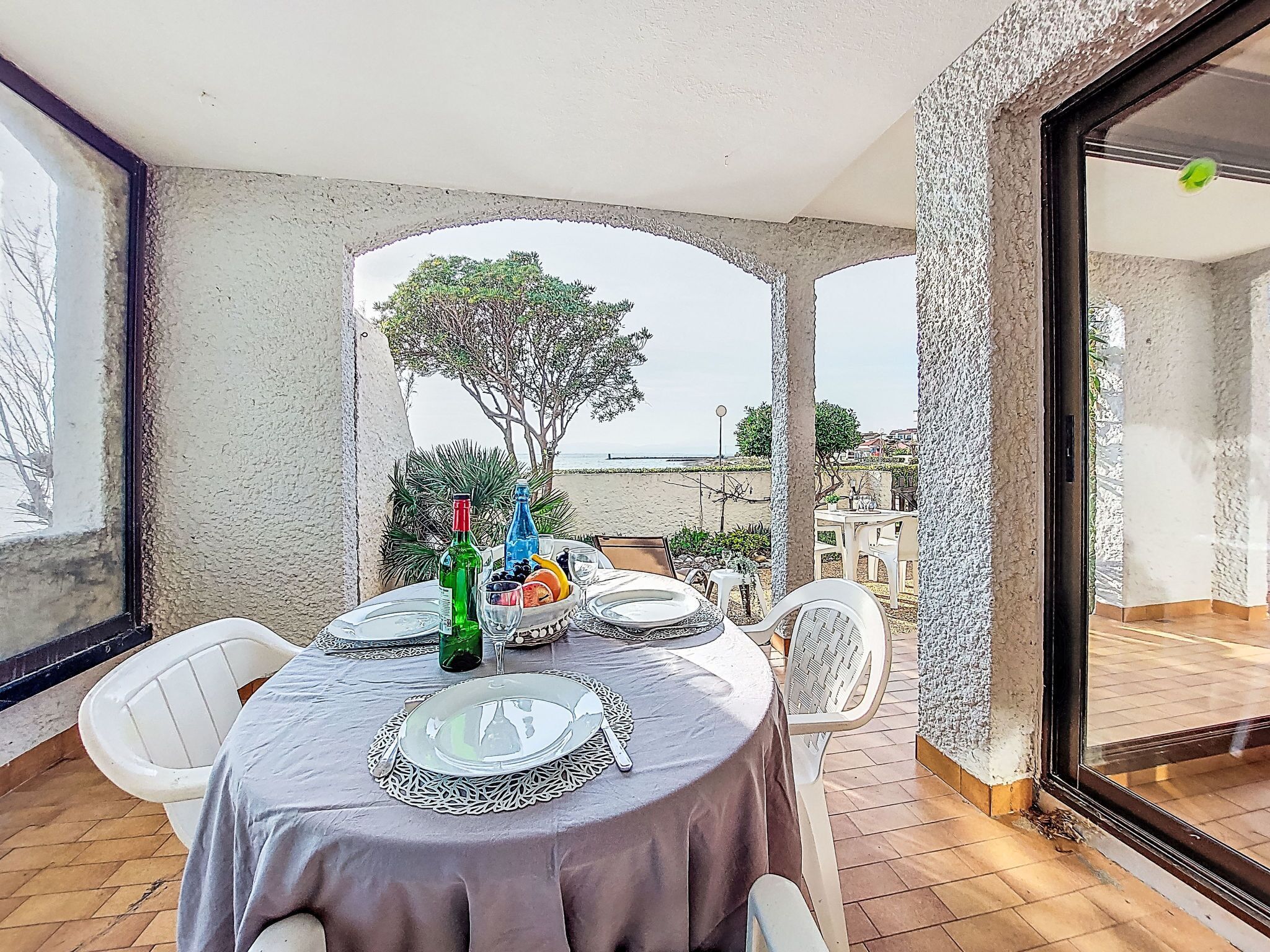 A dining area with a table set for two, a view of the beach, and a large window.