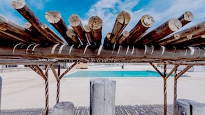 A wooden structure with logs, a pool, and a clear sky.