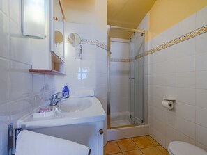 A bathroom with a white sink, a mirror, a shower, and a toilet. - Palmyra by Interhome (Le Barcarès)