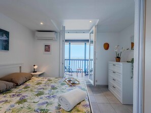 Ein Schlafzimmer mit Bett, Nachttisch und Blick auf den Balkon.