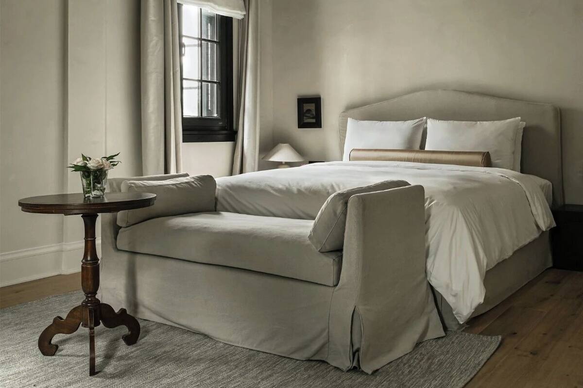 Une chambre à coucher avec un lit, une petite table ronde et une fenêtre avec des rideaux.