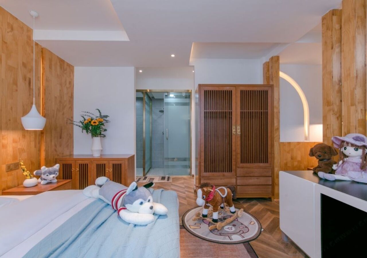 A modern hotel room with a bed, a desk, a wardrobe, and a shower area.