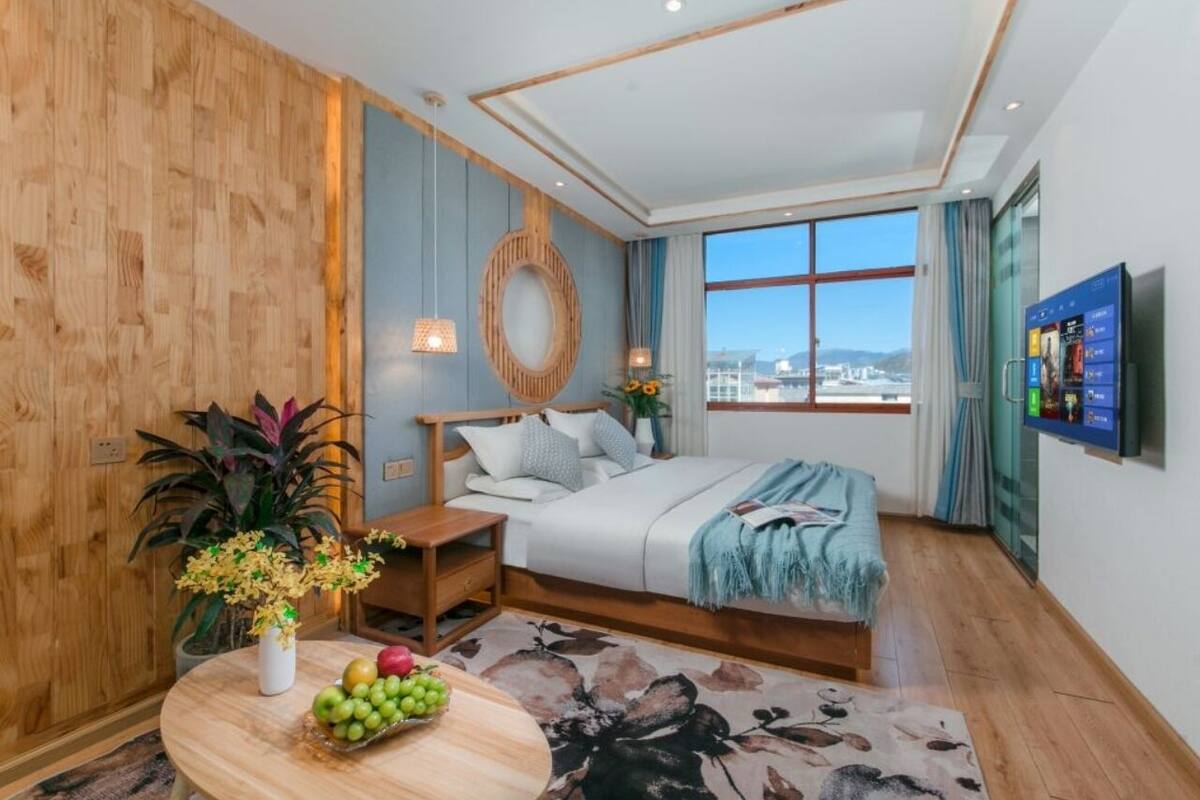 Un dormitorio moderno con una cama grande, una pared de madera, un cabecero redondo tejido, un televisor y vistas de la ciudad.