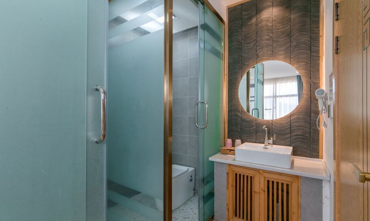 A modern bathroom with a glass shower enclosure, a wooden vanity with a sink, and a large mirror.