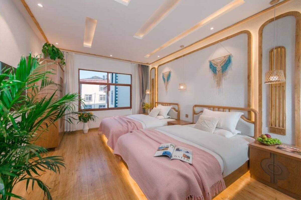 Una habitación de hotel moderna con dos camas, un ventanal con vistas a la ciudad, suelo de madera y decoración artística en las paredes.