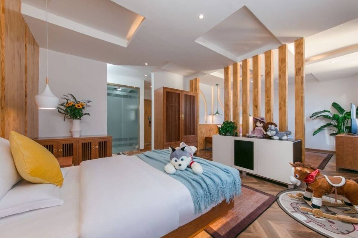 Una habitación de hotel moderna con una cama grande, detalles de madera, un escritorio y un pequeño rincón de descanso.