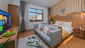 A modern hotel room with a wooden slat wall, a large window with curtains, a grey sofa, a bed with white bedding, and a wooden nightstand. - Yunyin Sanqiu Inn (Deqin)