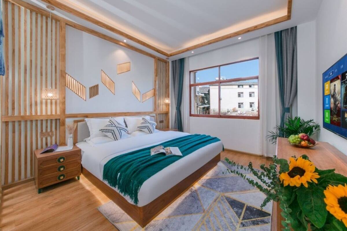 Un dormitorio moderno con una cama grande, cabecera de madera y vistas a la ciudad a través de un ventanal amplio.