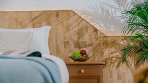 A bedroom with a wooden headboard, a bedside table with a fruit bowl, and a nightstand with a drawer. - Yunyin Sanqiu Inn (Deqin)