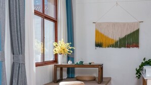 A room with a wooden bench, a small table with a vase of flowers, and a wall hanging. - Yunyin Sanqiu Inn (Deqin)