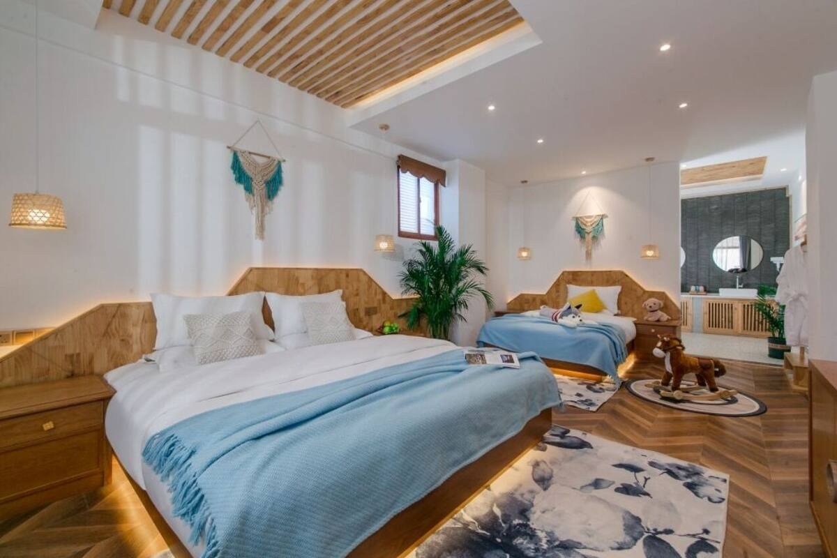 Una habitación de hotel moderna con dos camas, techo de madera y un espejo grande.