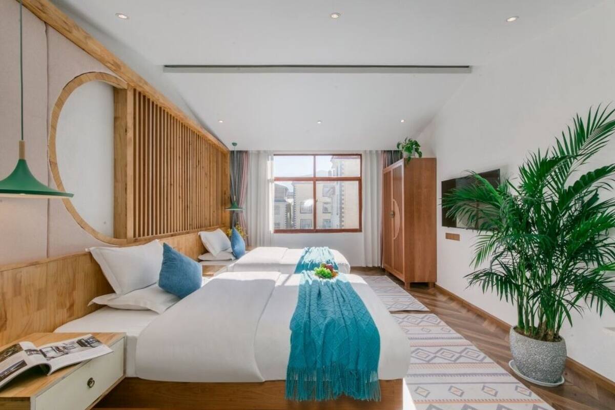 Habitación de hotel moderna con una cama grande, cabecera de madera, vista a la ciudad y una planta en maceta.
