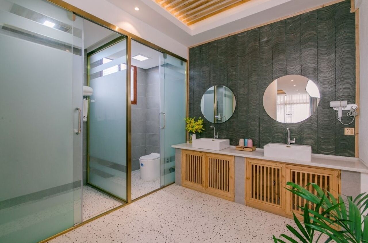 Een moderne badkamer met een douchecabine van glas, een wastafel met twee wasbakken en een grote spiegel.