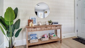 A wooden console table with a mirror above it, set against a textured wall. - Hot Tub + Big Yard • Minutes from Uptown! (Charlotte)