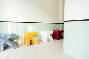 Un couloir dans lequel on a disposé quatre tabourets colorés en rangée.