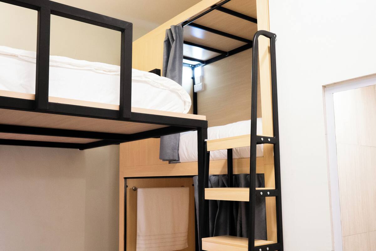 A bunk bed room with a ladder, a towel hanging, and a door.