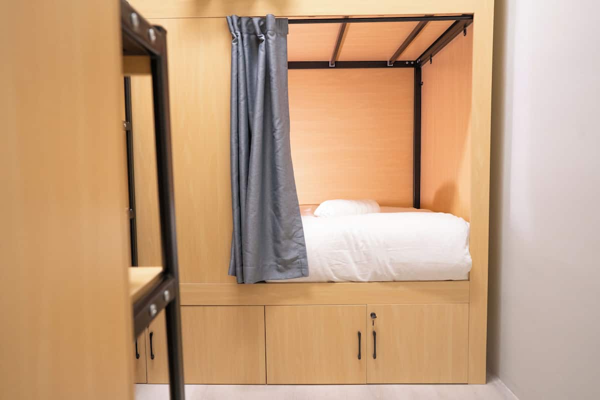 A compact room with a bed, a wardrobe, and a curtain.