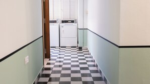 A narrow hallway with a checkered floor, a washing machine, and a dryer. - Code Hostel at Kampong Glam (Singapore)
