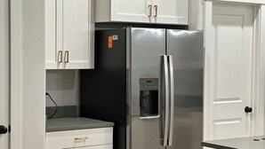 Eine Küche mit weißen Schränken, einem Edelstahlkühlschrank und einem Wasserspender.