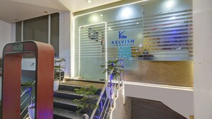 A hotel entrance with a glass facade, a staircase with plants, and a sign reading "KELVISH HOTEL". - Hotel The Kelvish Delhi Airport (New Delhi)